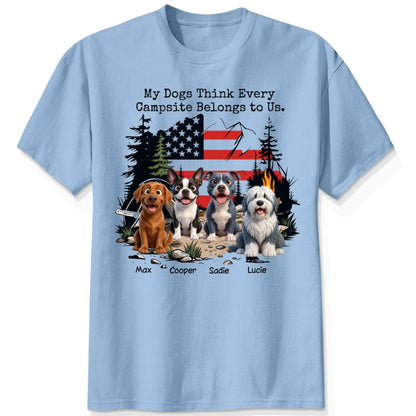 A blue short-sleeve t-shirt featuring a graphic print of dogs sitting in front of a campfire and an American flag, with the text 'My Dogs Think Every Campsite Belongs to Us.' and custom with dog's names below.