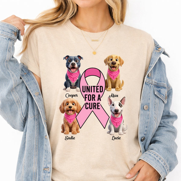 A woman wearing a sand graphic t-shirt with a pink ribbon and dogs wearing pink bandanas, layered under a light blue denim jacket.