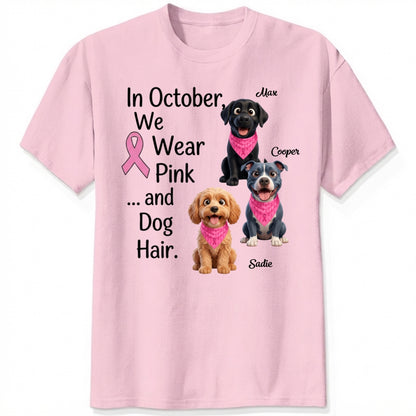A light pink short-sleeve crewneck t-shirt featuring a graphic print with three dogs wearing pink bandanas and the text 'In October, We Wear Pink and Dog Hair.'