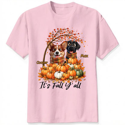 A pink short-sleeve crewneck t-shirt featuring a custom autumn graphic of custom dogs sitting on a pile of pumpkins under an orange tree, with the text 'It's Fall Y'all' and custom dog's names