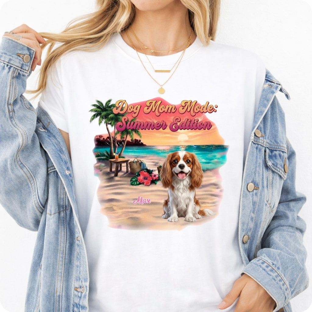 A woman wearing a white graphic t-shirt with a colorful 'Dog Mom Mode: Summer Edition' print featuring a dog on a beach, styled with an open light-wash denim jacket. 