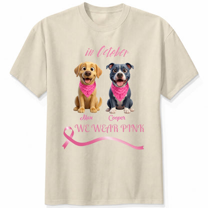 A sand short-sleeve crewneck t-shirt featuring a graphic print of dogs wearing pink bandanas, with the text 'in October', 'WE WEAR PINK' along with a pink ribbon. Personalized with a wide variety of dog breeds