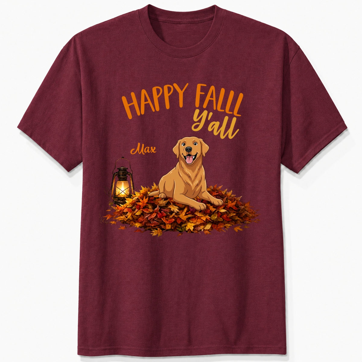 A maroon short-sleeve crewneck t-shirt featuring a 'Happy Fall Y'all' graphic with custom dogs sitting on a pile of autumn leaves next to a glowing lantern.