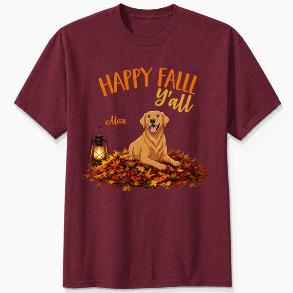 A maroon short-sleeve crewneck t-shirt featuring a 'Happy Fall Y'all' graphic with custom dogs sitting on a pile of autumn leaves next to a glowing lantern.