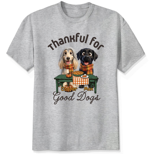 An ash gray short-sleeve crewneck t-shirt featuring a graphic print of custom dogs sitting at a table with autumn food, with the text 'Thankful for Good Dogs' and custom dog's names written around the illustration.