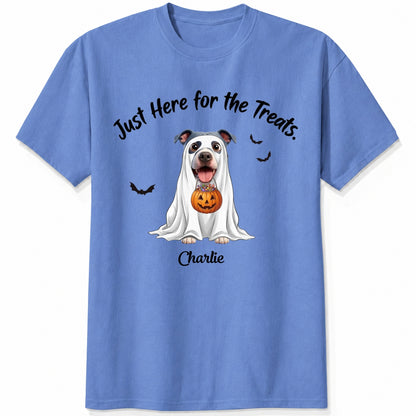 A blue t-shirt featuring a cartoon graphic of a dog dressed in a white ghost holding a jack-o'-lantern, with the text 'Just Here for the Treats.' and custom with dog's name printed below