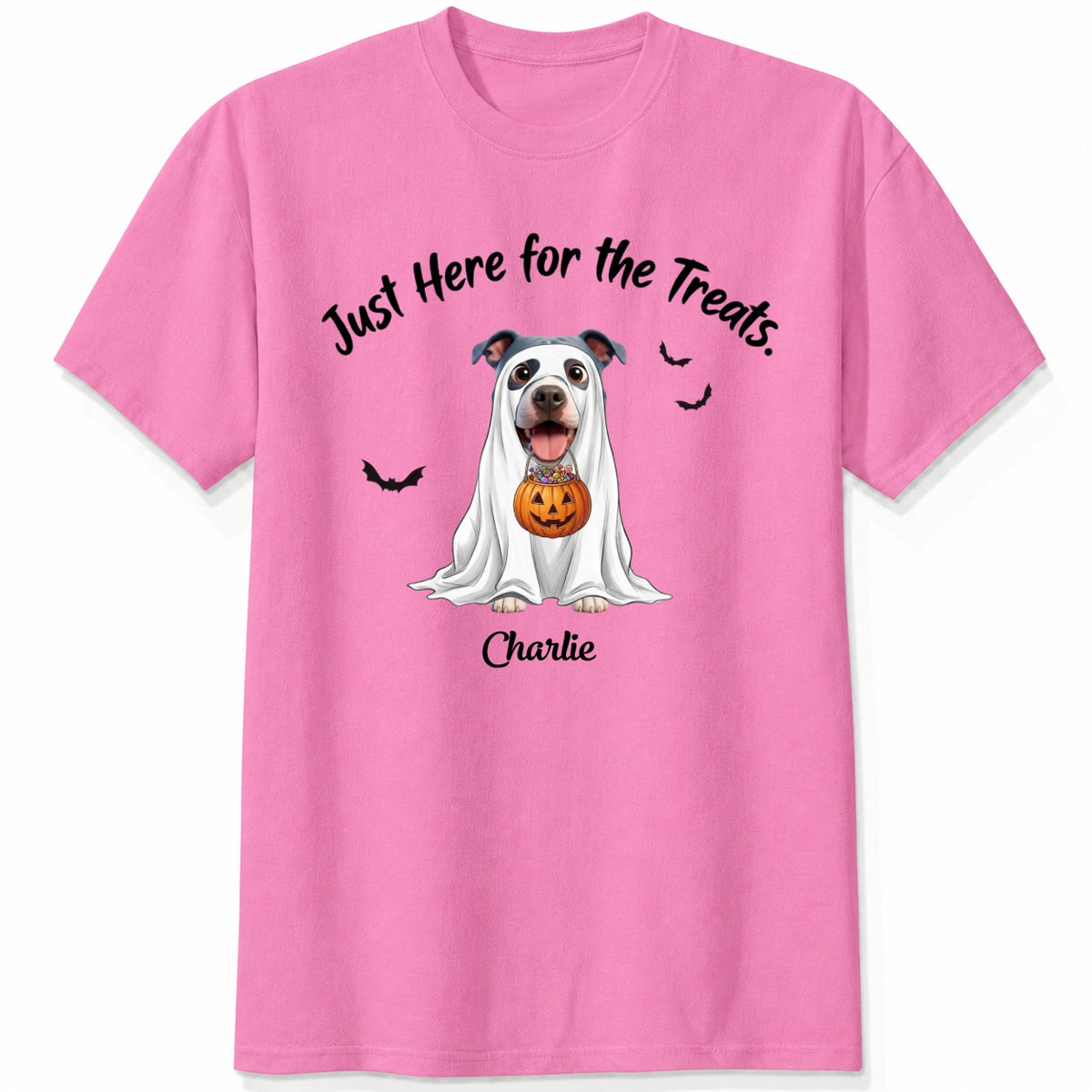 A pink t-shirt featuring a cartoon graphic of a dog dressed in a white ghost holding a jack-o'-lantern, with the text 'Just Here for the Treats.' and custom with dog's name printed below