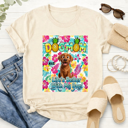 Asand custom dogs short-sleeve t-shirt featuring a colorful front graphic with the text 'DOG MOM' and 'Life's Better With My Dogs' alongside a cartoon dog and tropical floral background. The t-shirt is styled in a flat-lay arrangement with blue jeans, beige slide sandals, sunglasses, a burlap clutch, and a rope on a white wood background.