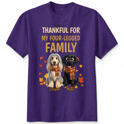 A purple short-sleeve crewneck t-shirt with a graphic print. The print features the text 'THANKFUL FOR MY FOUR-LEGGED FAMILY' in beige and orange lettering, above an illustration of custom dogs wearing orange plaid scarves, surrounded by autumn leaves. customized with dog's names