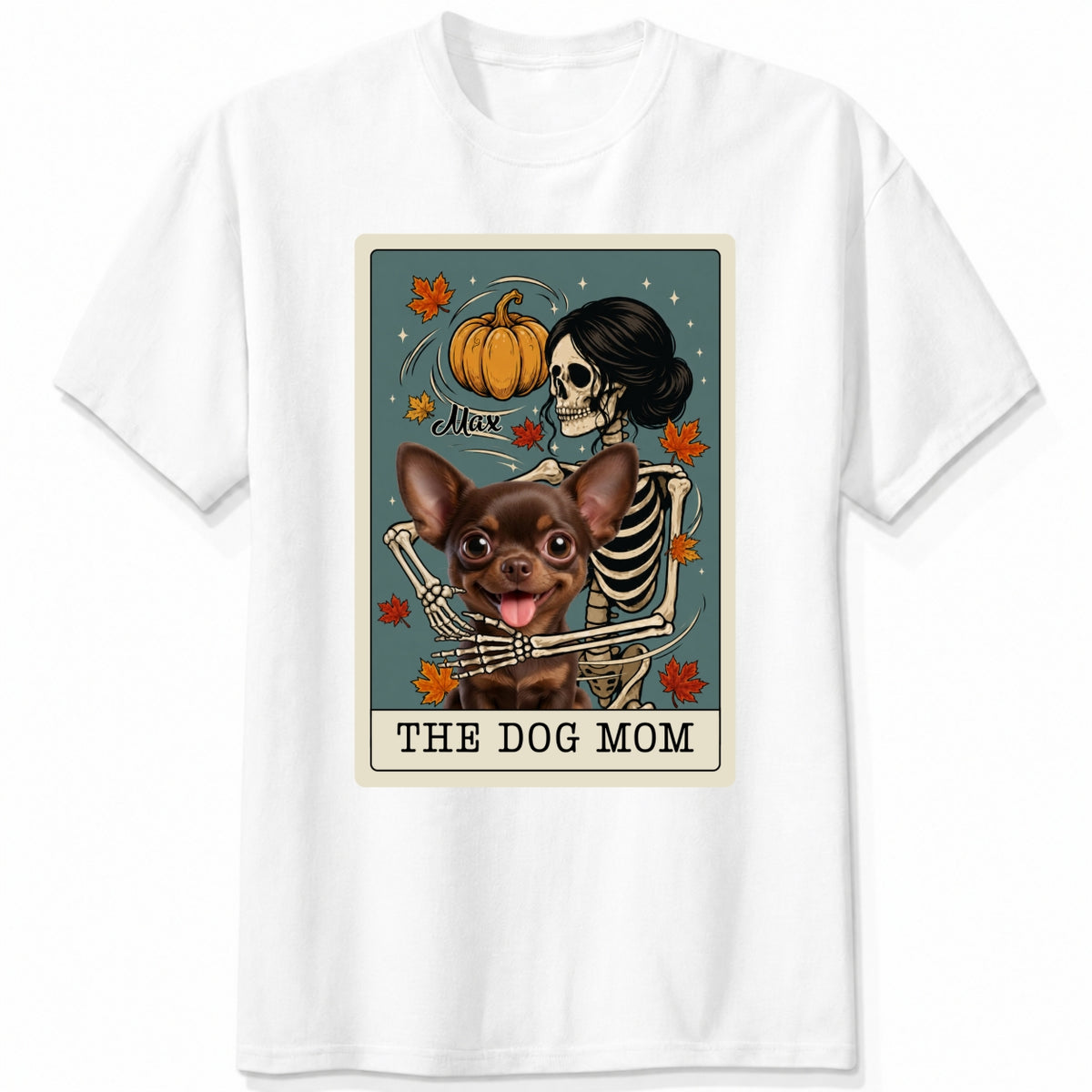 A white short-sleeve crewneck t-shirt featuring a graphic print of a skeleton dog mom and a custom dog under a autumn pumpkin, styled like a tarot card labeled 'THE DOG MOM'.