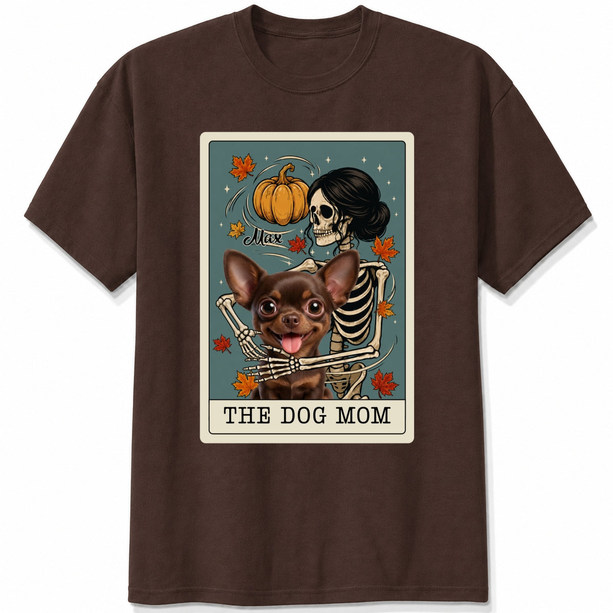 A dark chocolate short-sleeve crewneck t-shirt featuring a graphic print of a skeleton dog mom and a custom dog under a autumn pumpkin, styled like a tarot card labeled 'THE DOG MOM'.