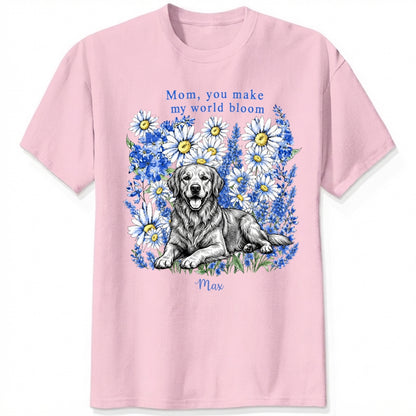 A pink custom dogs t-shirt featuring a graphic print of a golden retriever dog surrounded by blue flowers, with the text 'Mom, you make my world bloom' and dog's name written below.